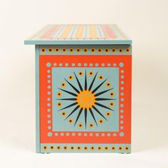 an orange and blue box sitting on top of a white surface with dots around it