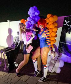 two women dressed up as clowns posing for the camera with balloons in front of them