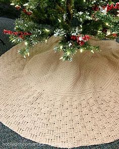 a crocheted christmas tree skirt with red berries and greenery on the top