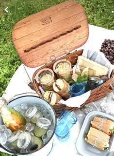 an open picnic basket filled with food on top of a white cloth covered tablecloth