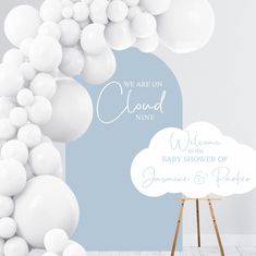 we are on cloud nine welcome baby shower sign with white balloons in the sky above it