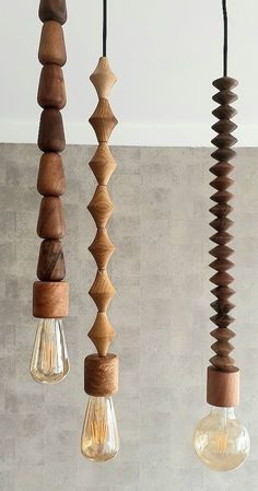 three light bulbs hanging from the ceiling with different shapes and sizes of wood on them