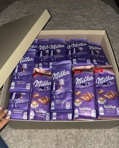 a box full of milk chocolates sitting on the floor next to someone's hand