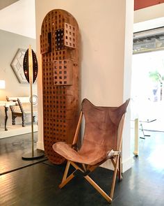 a wooden chair sitting in front of a wall sculpture