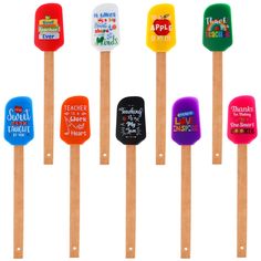 six wooden spatulas with different designs and sayings on them, all lined up against a white background