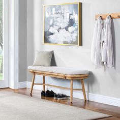 a wooden bench sitting in front of a painting on the wall next to a pair of shoes