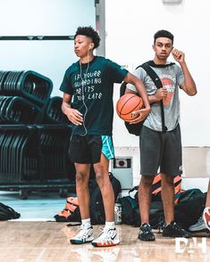 two young men standing next to each other with basketballs on the floor in front of them