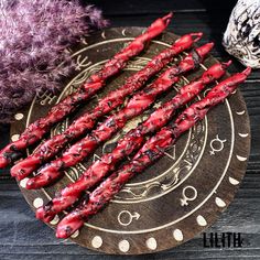 some red candles are sitting on a wooden plate next to purple and white balls of yarn