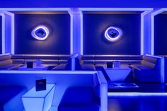 the interior of a modern restaurant with blue lighting and leather booths in front of them