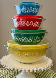 four glass bowls are stacked on top of each other in different colors and designs,