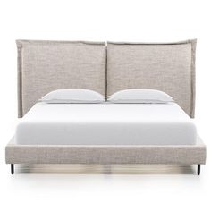 an upholstered bed with white sheets and pillows