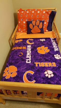 a bed with purple and orange bedspread that has clemson on it