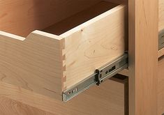 an open drawer in a wooden cabinet with metal pulls on the bottom and drawers below