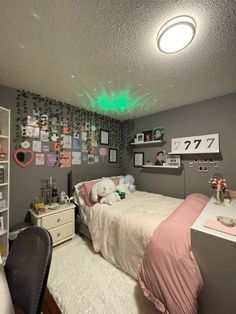 a bedroom with a bed, desk and pictures on the wall above it is lit by green light