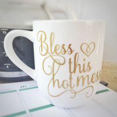 a white coffee mug with gold lettering that says,'bliss this hot mess '