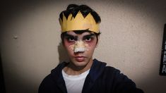 a young man wearing a yellow crown and bandaged nose with tape on his forehead