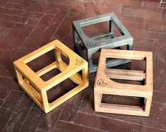 three wooden stools sitting on top of a tile floor next to each other,