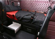 a bed in the back of a car with red and black sheets on it's headboard