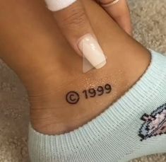 a woman's foot with a small tattoo on her left ankle and the word 999 written in black ink