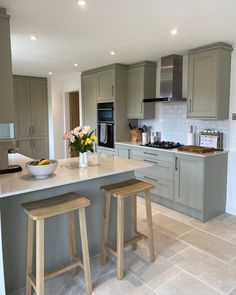 a kitchen with two stools in front of the counter and an island that has flowers on it