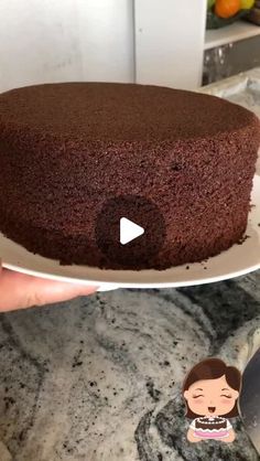 a person holding a plate with a chocolate cake on it and an emoticive sticker next to it