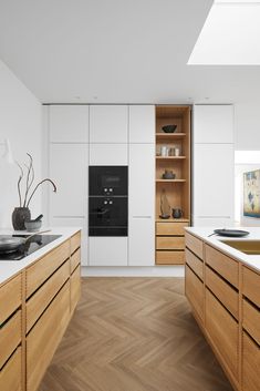 a kitchen with wooden cabinets and white walls, an oven in the center is surrounded by wood flooring