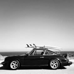 a black and white photo of a car with surfboards on top