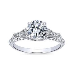 an 18k white gold round diamond engagement ring with filigrees on the band