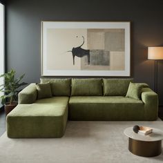 a living room with a large green couch and coffee table in front of a painting on the wall