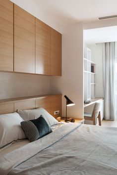 a large bed sitting next to a window in a room with wooden cabinets on both sides