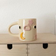 a coffee mug with a cow face on it sitting on top of a wooden dresser