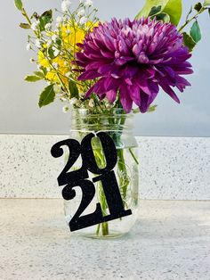 a vase filled with purple and yellow flowers sitting on top of a white countertop