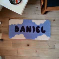 a door mat with the word daniel written in black ink on it, sitting on a wooden floor