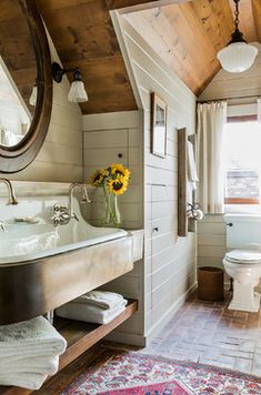 a white toilet sitting next to a sink in a bathroom under a wooden framed mirror