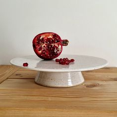 a pomegranate sitting on top of a white plate with some red seeds