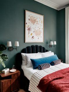 a bedroom with green walls and a red blanket on the bed, along with two lamps