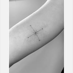 a small cross tattoo on the left inner arm and shoulder, in black and white