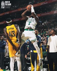 a basketball player jumping up to dunk the ball in front of other players and fans