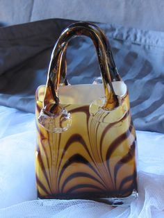 a brown and white handbag sitting on top of a bed next to a pillow