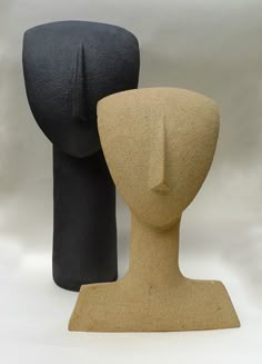 two clay mannequin heads are standing next to each other on a white background