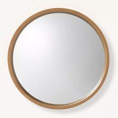 a round mirror on the wall with a wooden frame and wood trim around it's edge