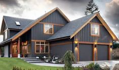 a large gray house sitting on top of a lush green field next to a forest