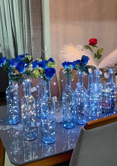 there are many vases with blue flowers in them on the dining room table,