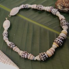 a close up of a necklace on a palm leaf with shells and seashells