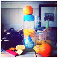 oranges and lemons are sitting on the counter next to a blender with a blue lid