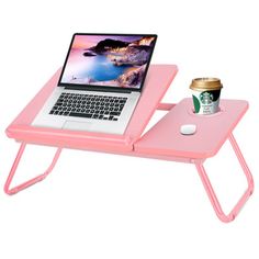 a laptop computer sitting on top of a pink table with a cup of coffee next to it