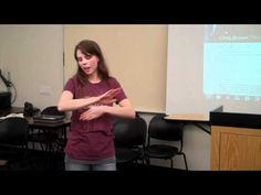 a woman standing in front of a projector screen holding her hands out to the side