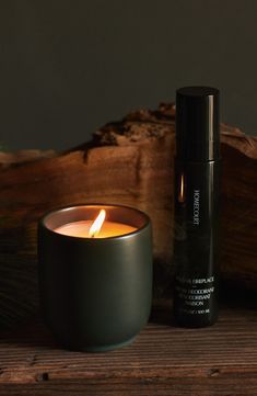 a candle sitting on top of a wooden table next to a bottle