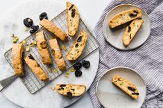 blueberry scones are cooling on a wire rack next to two plates with slices