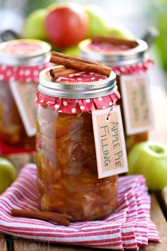 two jars filled with apple cider sitting on top of a table next to apples